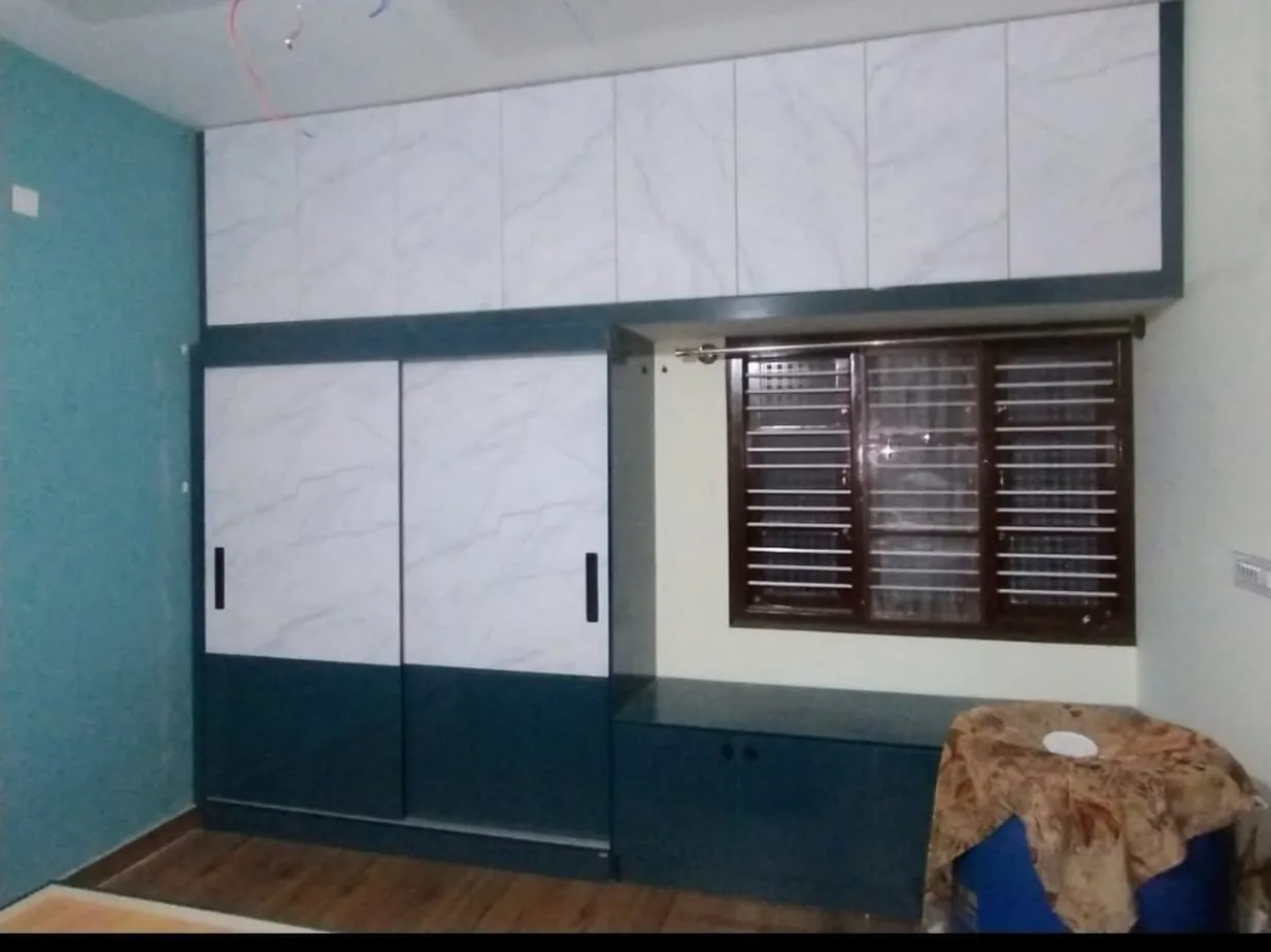 Teal and white sliding wardrobe beside a window